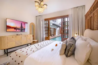 a bedroom with a large white bed and a television at Villa Casa Adeline in Canggu