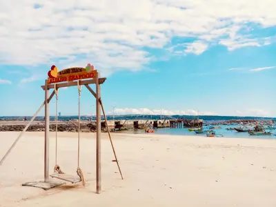 a lifeguard stand on a beach with people in the water at Familytel Bali in Jimbaran