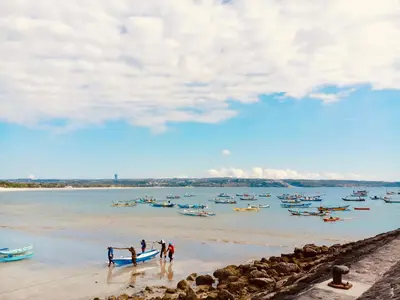 a group of people on a beach with boats in the water at Familytel Bali in Jimbaran