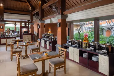 a restaurant with tables and chairs and pots and pans at Adi Dharma Hotel Kuta in Kuta