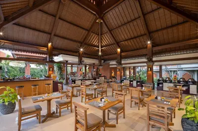a restaurant with wooden tables and chairs and a large ceiling at Adi Dharma Hotel Kuta in Kuta