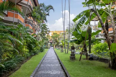a walkway in the middle of a building with plants at Adi Dharma Hotel Kuta in Kuta