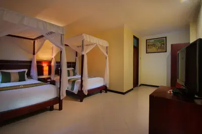 a bedroom with two beds and a flat screen tv at Adi Dharma Hotel Legian in Legian