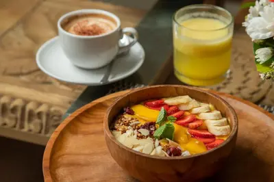 a bowl of fruit and a cup of coffee and a glass of orange juice at The Luxury Collection, Monaco Blu in Seminyak