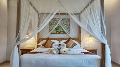 a bedroom with a canopy bed with white curtains at Sarayu Villa in Seminyak