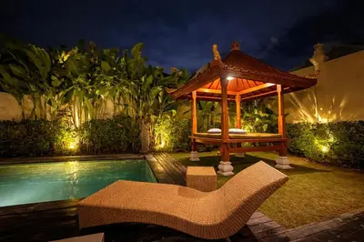 a gazebo next to a swimming pool at night at Sarayu Villa in Seminyak