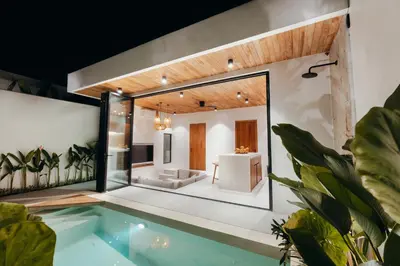 a house with a swimming pool and a living room at La Payesa in Canggu