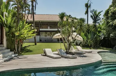 a pool with chaise lounge chairs next to a house at La Payesa in Canggu
