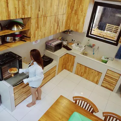 a woman is standing in a kitchen cooking in an oven at Metta Agara in Kerobokan