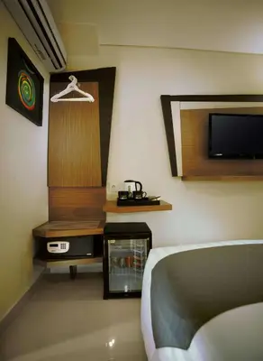 a bedroom with a bed and a tv on a wall at Hotel Neo - Kuta, Jelantik in Legian
