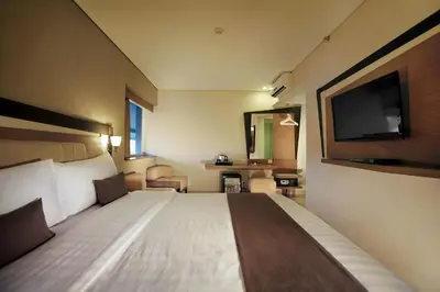 a hotel room with a bed and a flat screen tv at Hotel Neo - Kuta, Jelantik in Legian