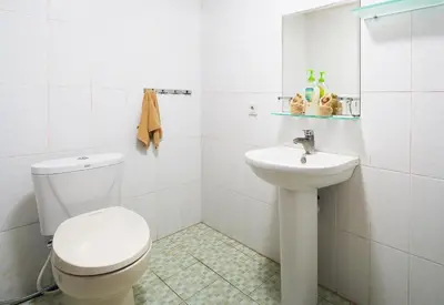 a white bathroom with a toilet and a sink at Kyara Villa Apartments in Canggu
