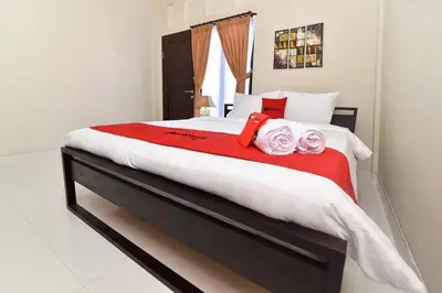 a bedroom with a large bed with red and white at RedDoorz Plus near Jalan Imam Bonjol Denpasar in Seminyak
