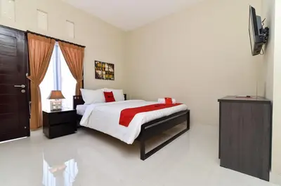 a bedroom with a bed and a television in it at RedDoorz Plus near Jalan Imam Bonjol Denpasar in Seminyak