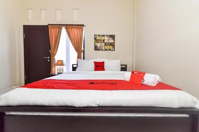 a bedroom with a large bed with red and white pillows at RedDoorz Plus near Jalan Imam Bonjol Denpasar in Seminyak