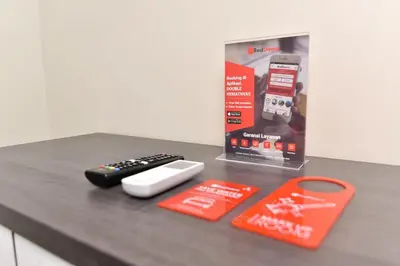 a table with two remote controls and a box at RedDoorz Plus near Jalan Imam Bonjol Denpasar in Seminyak