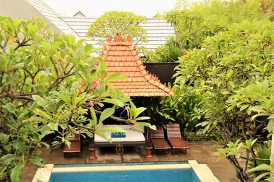 a garden with a swimming pool and a house at The Nibbana Villas in Seminyak