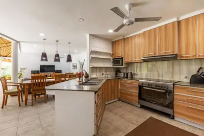 a kitchen with wooden cabinets and a table with chairs at Elina Villas Seminyak in Seminyak