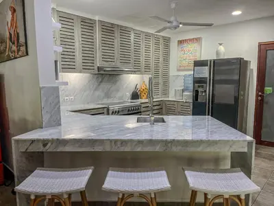 a kitchen with a large counter with three stools at Elina Villas Seminyak in Seminyak