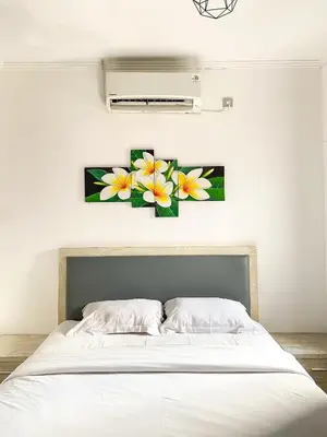 a bedroom with a bed with two flowers on the wall at ALA Hostel in Seminyak