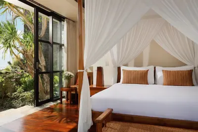 a bedroom with a white bed and a large window at Villa Jamalu by Nakula in Jimbaran