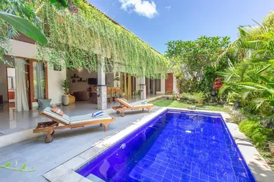 a swimming pool with two chairs and a house at MasBro ART Villas in Seminyak