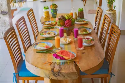 a long wooden table with plates of food on it at MasBro ART Villas in Seminyak