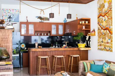 a kitchen with a bar with stools at MasBro ART Villas in Seminyak