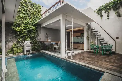 a house with a swimming pool next to a house at Ayona Villa Seminyak by Ini Vie Hospitality in Seminyak