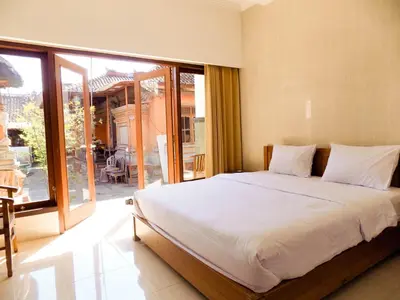 a bedroom with a large bed and a large window at Guna Graha Kuta by Kamara in Kuta