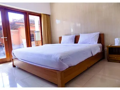 a bedroom with a large bed with white sheets at Guna Graha Kuta by Kamara in Kuta