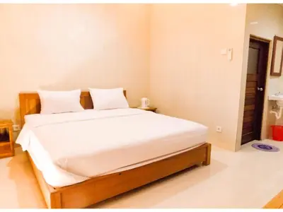 a bedroom with a large bed with white sheets at Guna Graha Kuta by Kamara in Kuta