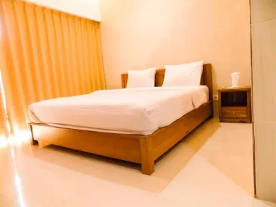 a bedroom with a bed with white sheets and pillows at Guna Graha Kuta by Kamara in Kuta