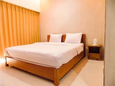 a bedroom with a large bed with white sheets at Guna Graha Kuta by Kamara in Kuta