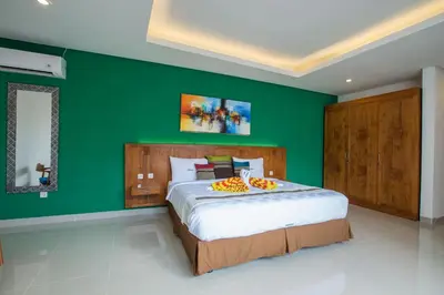 a bedroom with a green wall and a large bed at Villa Ultima Umalas in Canggu