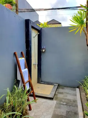 a wooden chair sitting in front of a blue wall at Villa Davenny in Seminyak