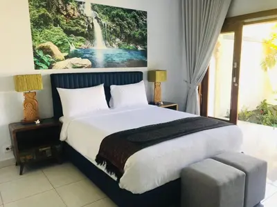 a bedroom with a large bed with a waterfall painting on the wall at Villa Pintu Biru in Seminyak