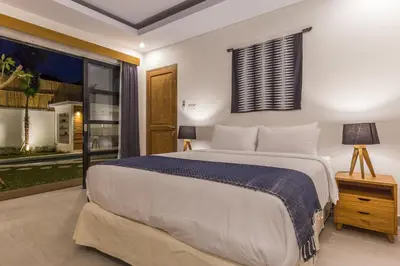 a bedroom with a large bed and a window at Villa Jamu in Seminyak