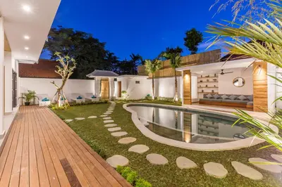 a home with a swimming pool and a yard at Villa Jamu in Seminyak