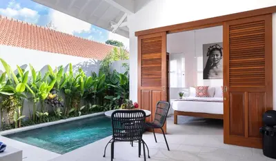 a bedroom with a pool and a table and chairs at Villa Karang in Seminyak