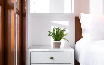 a white nightstand with a plant on it next to a bed at Villa Karang in Seminyak