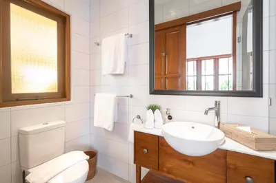 a bathroom with a sink and a toilet and a mirror at Villa Chikka in Seminyak