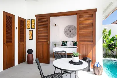 a room with a bed and a table and chairs at Villa Pandi in Seminyak