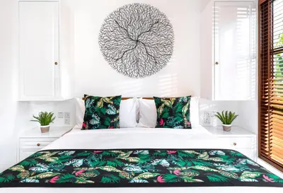 a white bedroom with a bed with a tree picture on the wall at Villa Pandi in Seminyak