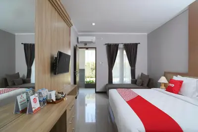 a hotel room with a bed and a television at Capital O 2166 Elitya Stay in Sanur
