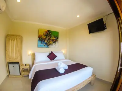 a bedroom with a large white bed and a tv at Dana Homestay in Canggu