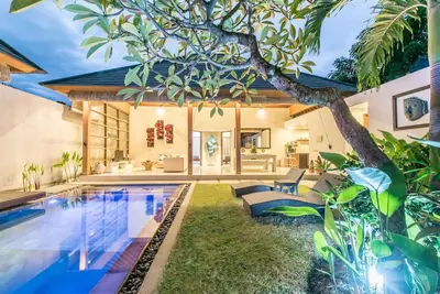a house with a swimming pool and a tree at Manis, Luxury 3 Bedroom Heart of Seminyak in Seminyak