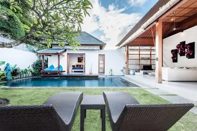 a backyard with a pool and two chairs and a table at Manis, Luxury 3 Bedroom Heart of Seminyak in Seminyak