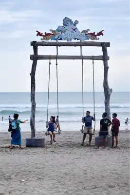 a group of people standing under a swing set on the beach at Del Cielo Villa Seminyak in Seminyak