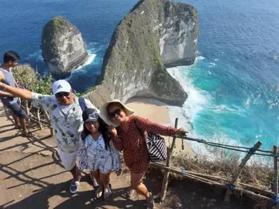 a family standing on the edge of a cliff overlooking the ocean at D&D homestay in Pesanggaran